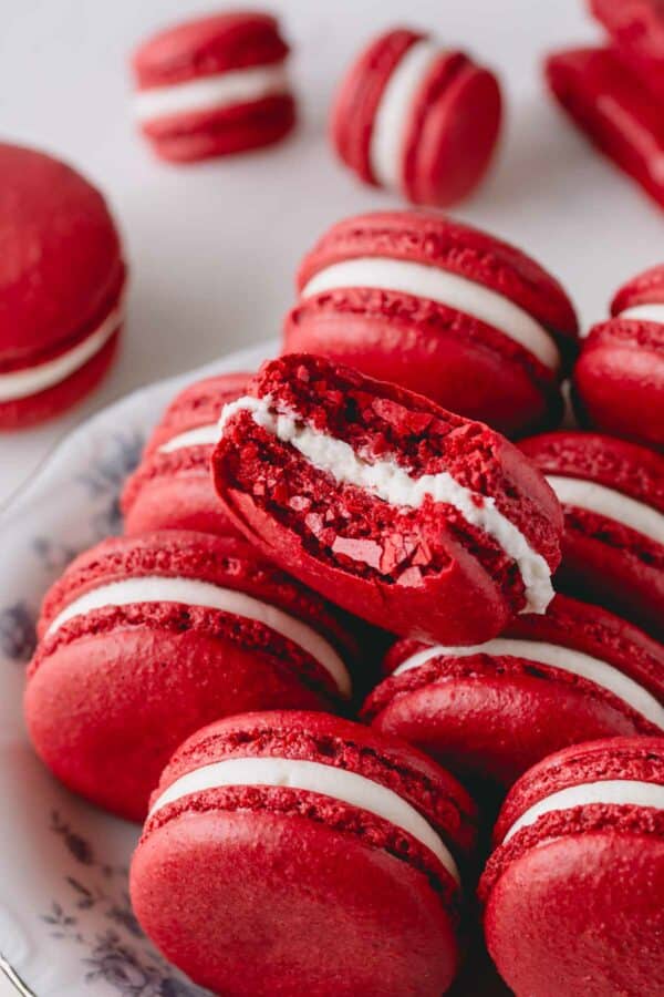 Red velvet macarons on a plate with one macaron bitten.
